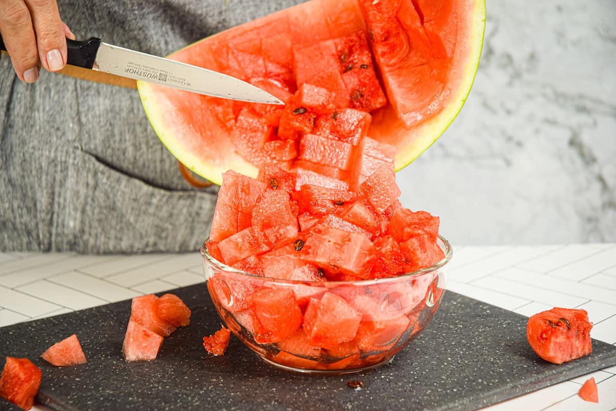Watermelon cubes falling into bowl.