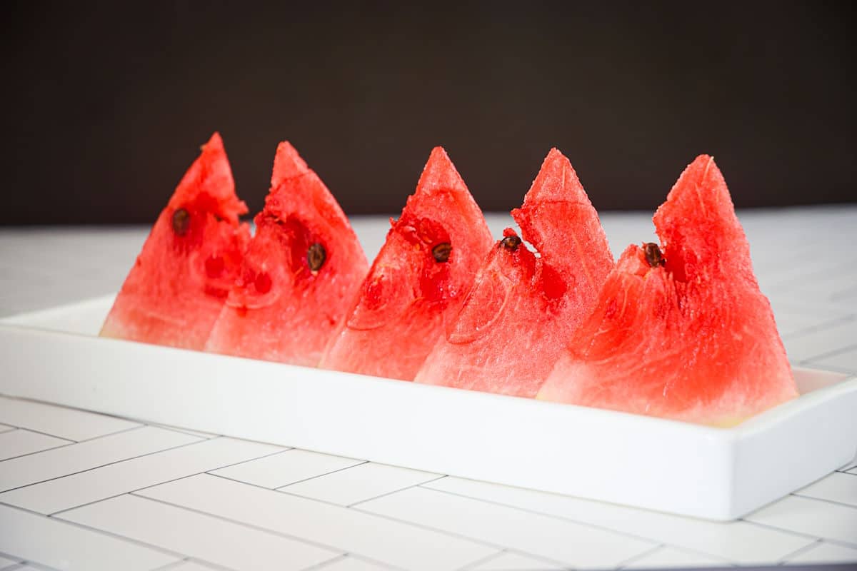 Watermelon triangles standing up on white dish.