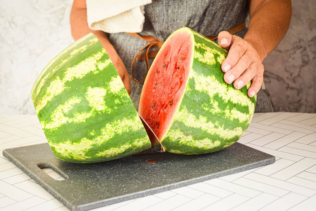Woman slicing large watermelon in half.