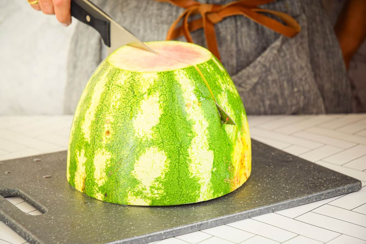 Woman slicing watermelon into quarters.