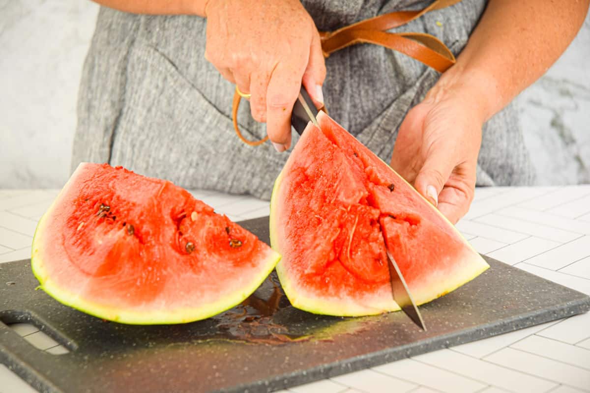 Woman slicing watermelon into smaller wedges.