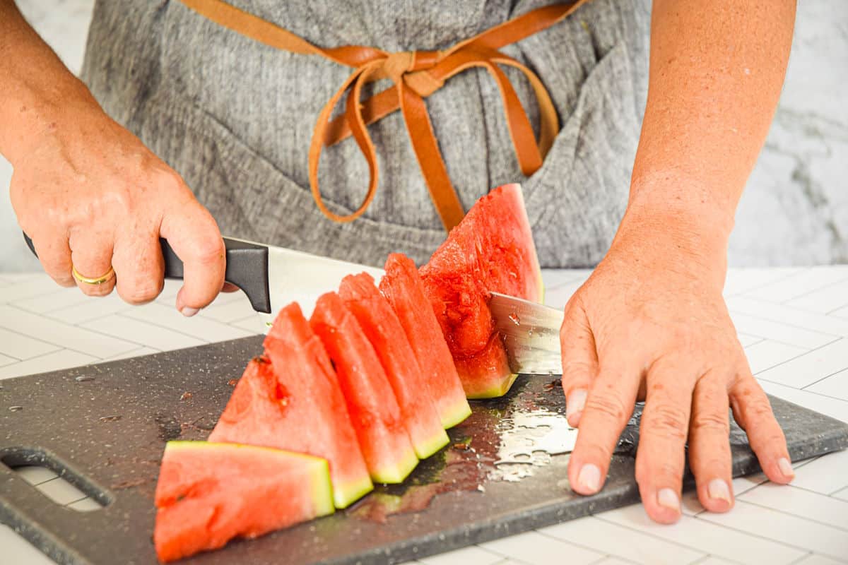 Watermelon wedge getting sliced into triangles.