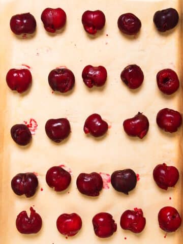 Fresh cherries on parchment lined sheet pan.