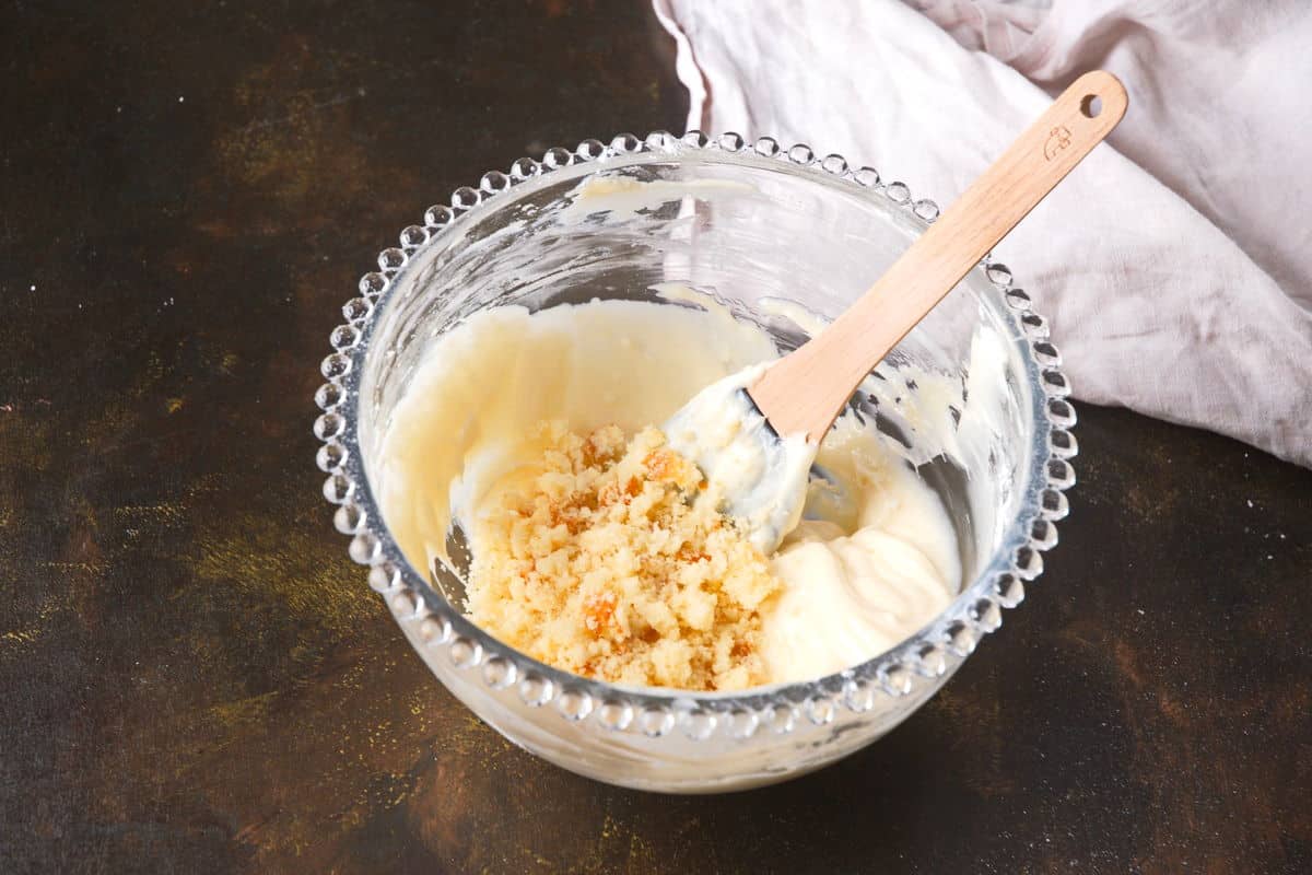 Cake pop frosting in bowl with crumbled vanilla cake.