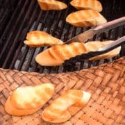 Grilled bread on outdoor grill with tongs.