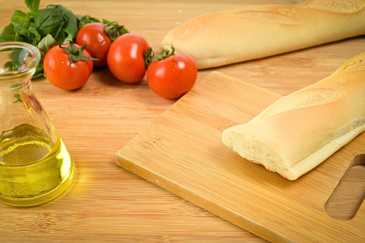 Bread, tomatoes and olive oil on cutting board.