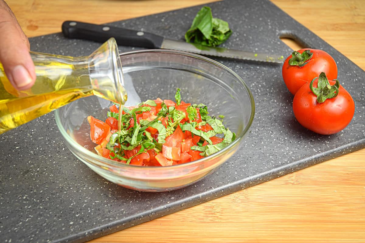 Bruschetta in small bowl with tomatoes on the side.