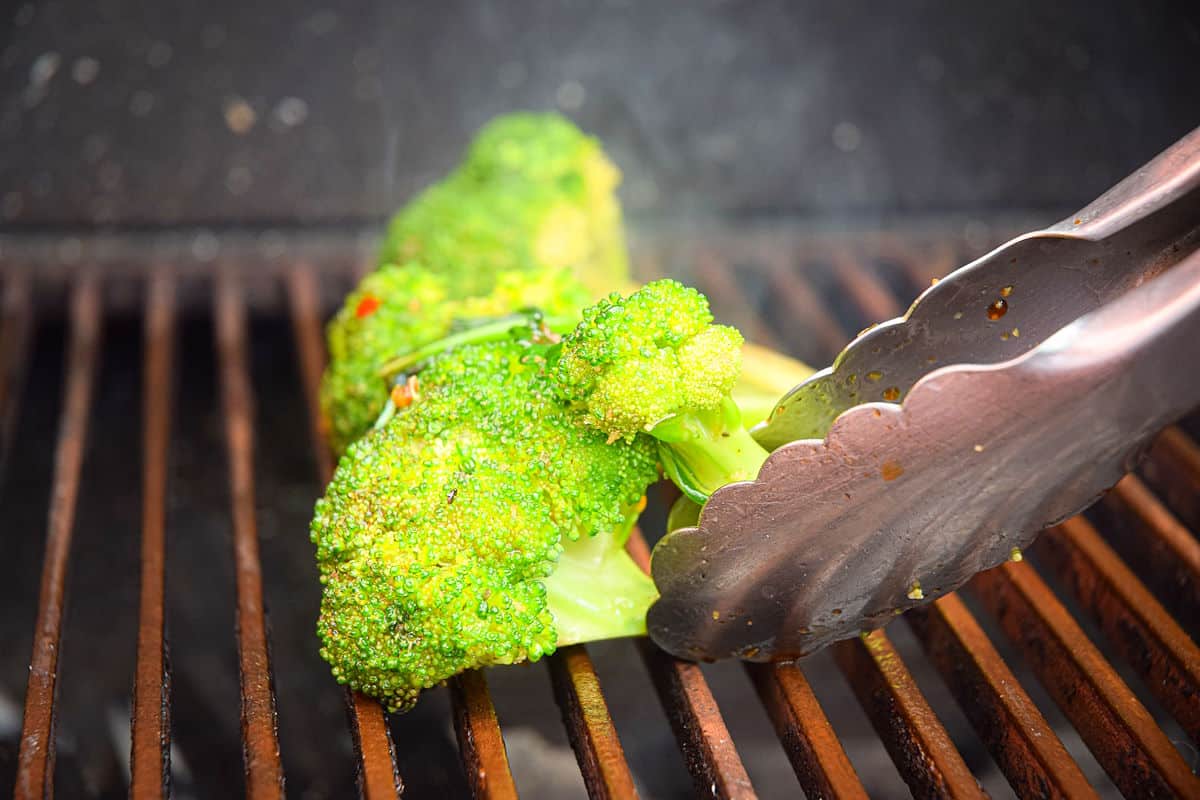 Broccoli on the grill in tongs.