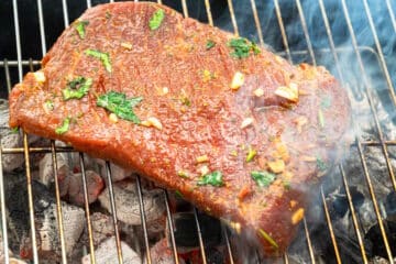 Marinated flank steak on outdoor grill.
