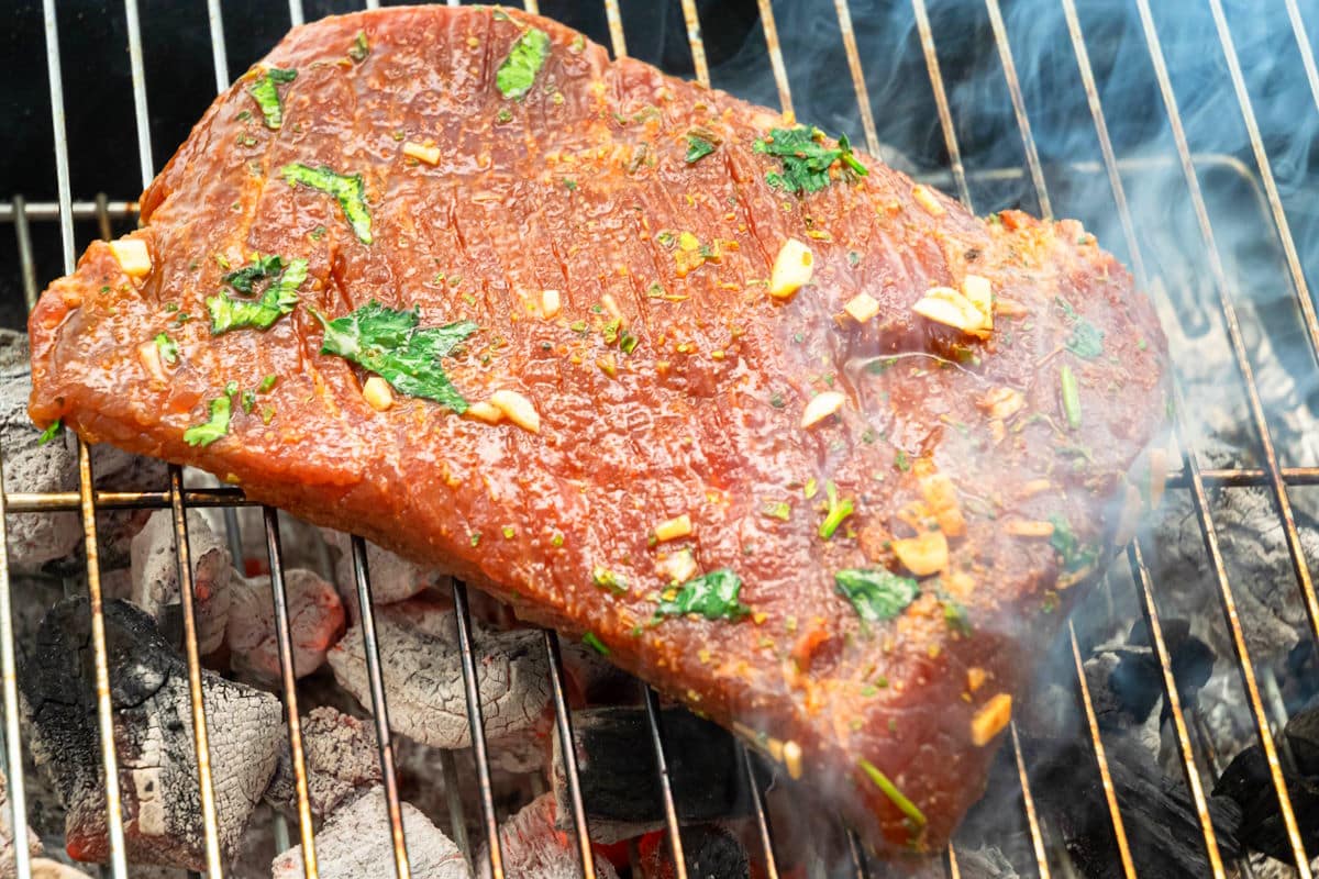 Marinated flank steak on outdoor grill.