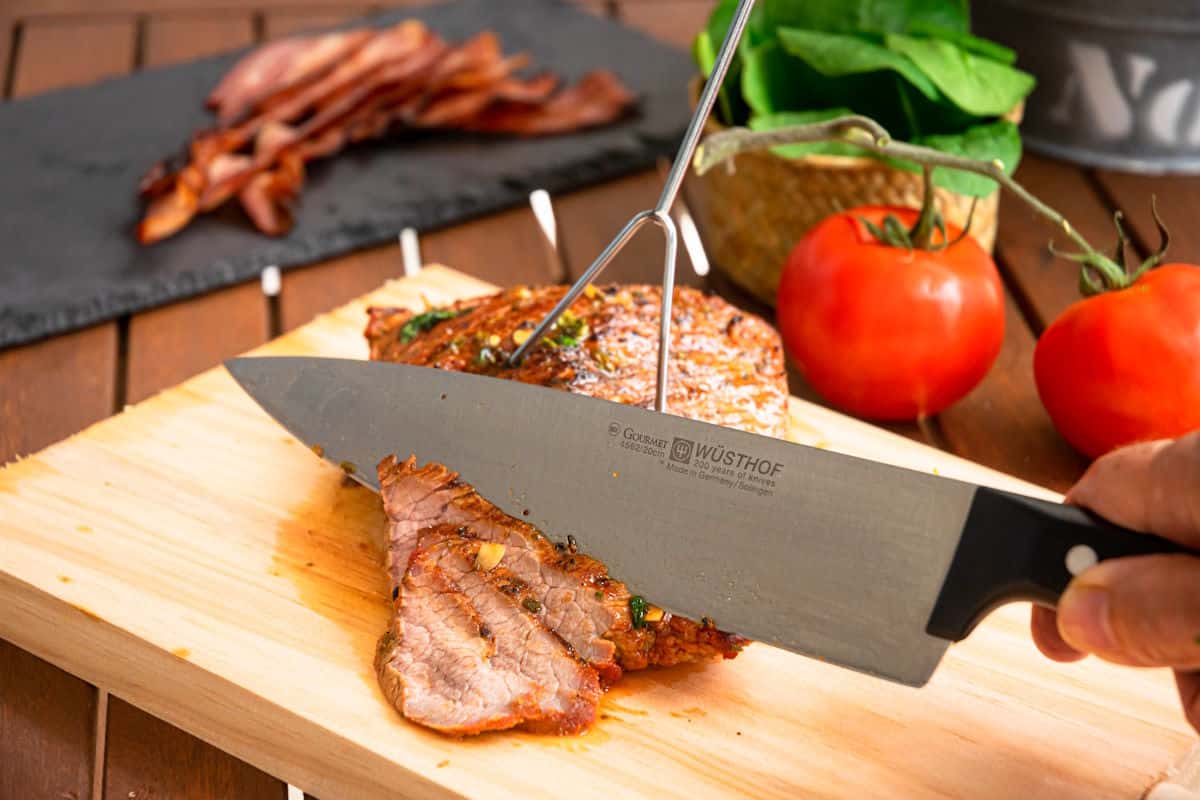 Carne asada steak getting sliced with chef's knife.