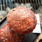 Grilled burgers on metal flipper, grill grates in the background.