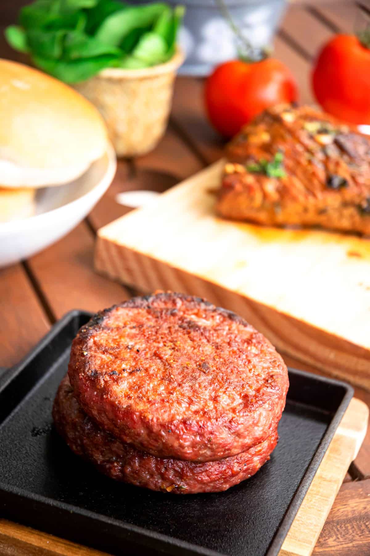 Grilled burgers stacked on cast iron dish.