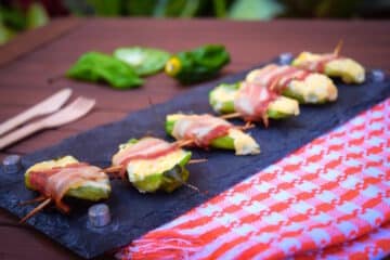 Grilled jalapeño poppers on serving board with toothpicks.