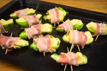 Uncooked jalapeño poppers on baking sheet.