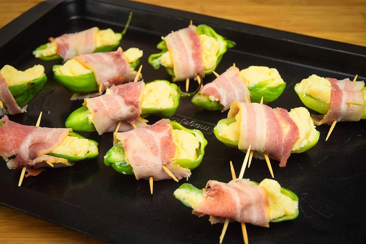 Uncooked jalapeño poppers on baking sheet.