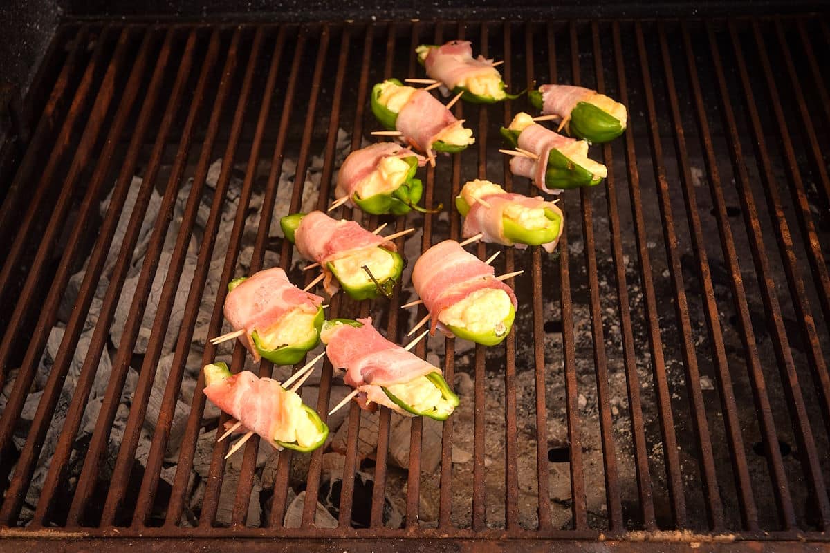 Uncooked jalapeño poppers on grill.