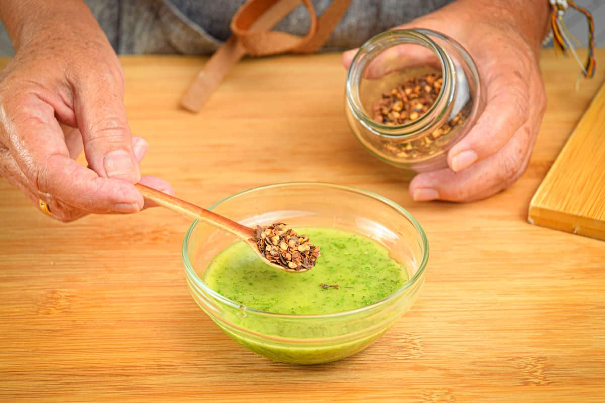 Chimichurri sauce in small bowl with red pepper flakes.