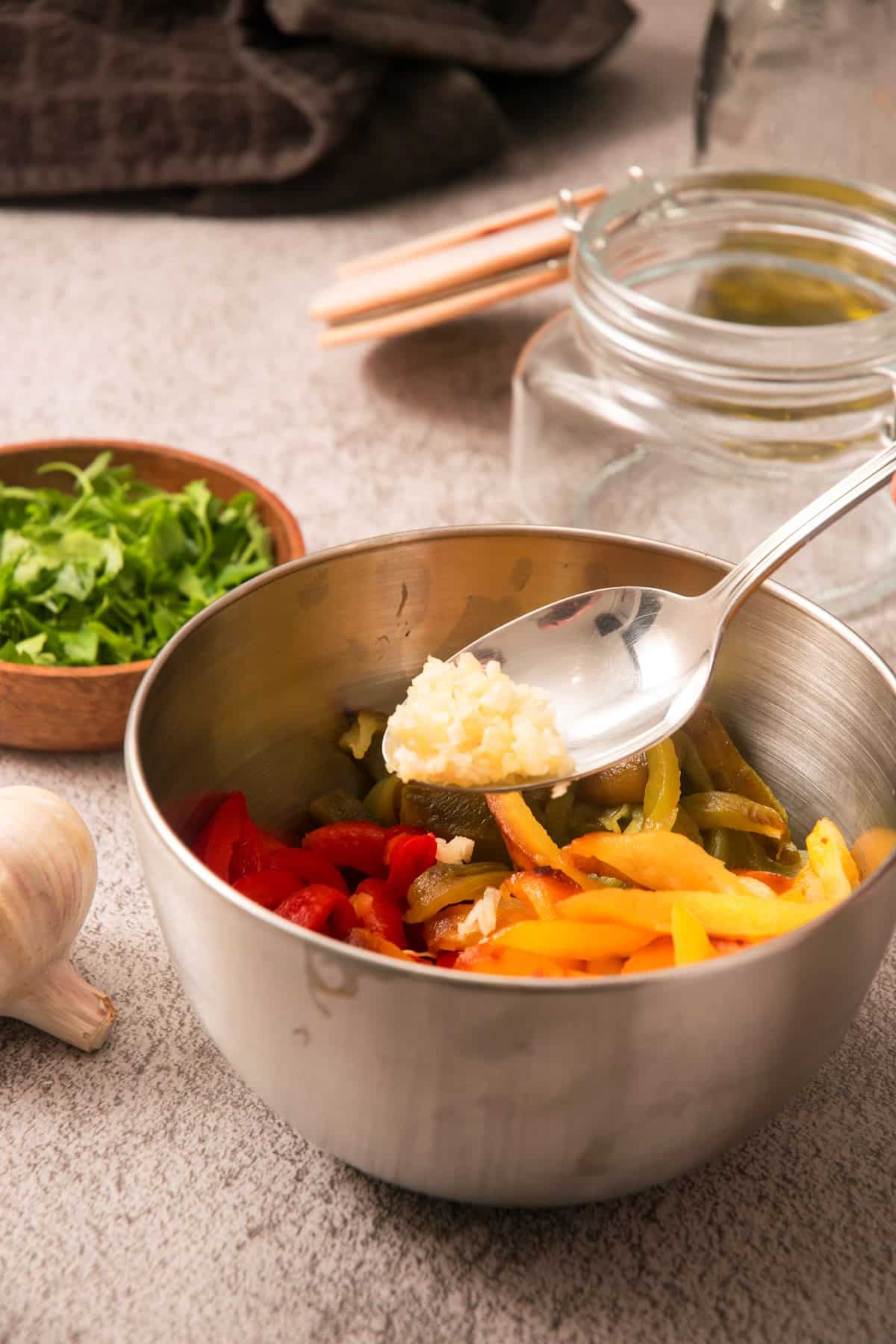 Grilled, sliced bell peppers in bowl with garlic.