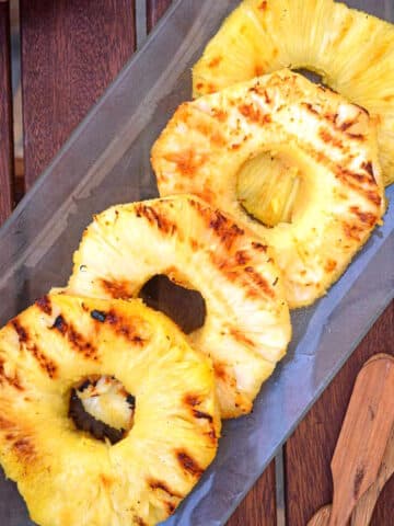 Grilled pineapple rings on serving dish.