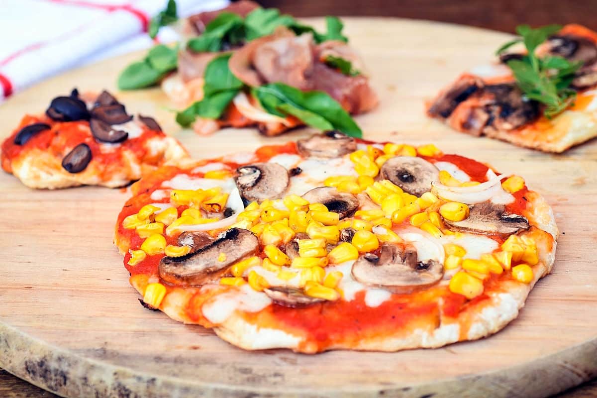 Grilled pizza with toppings on wooden board.