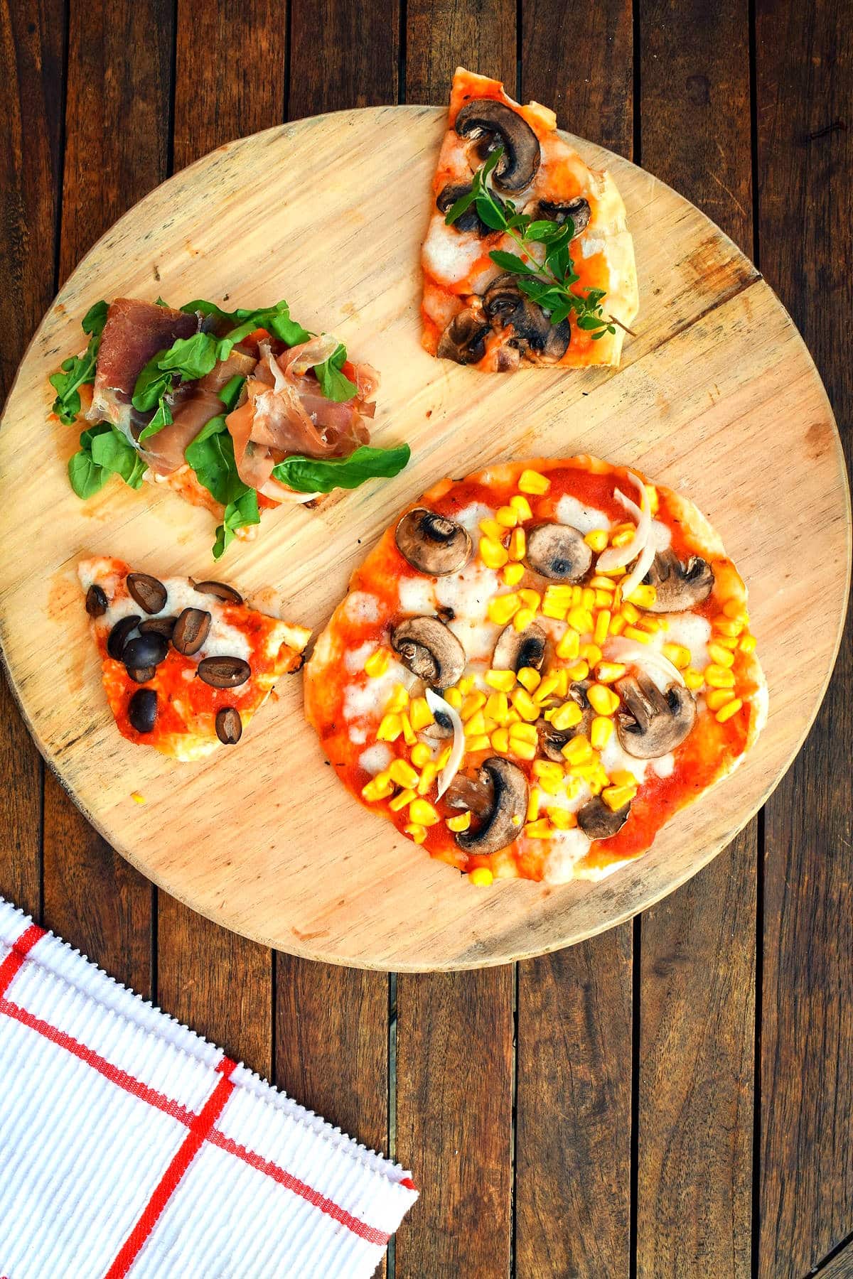 Grilled pizza with toppings on circular wooden board.