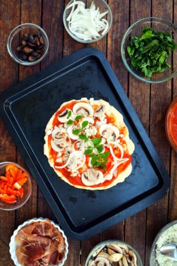Raw pizza dough on baking sheet with toppings.