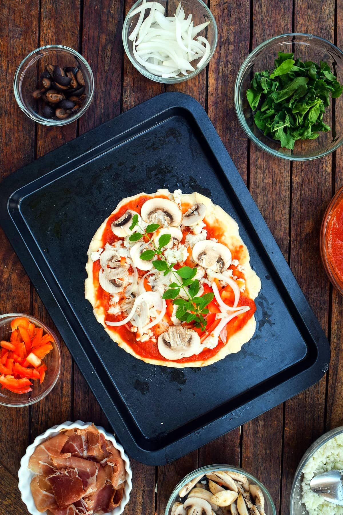 Raw pizza dough on baking sheet with toppings.