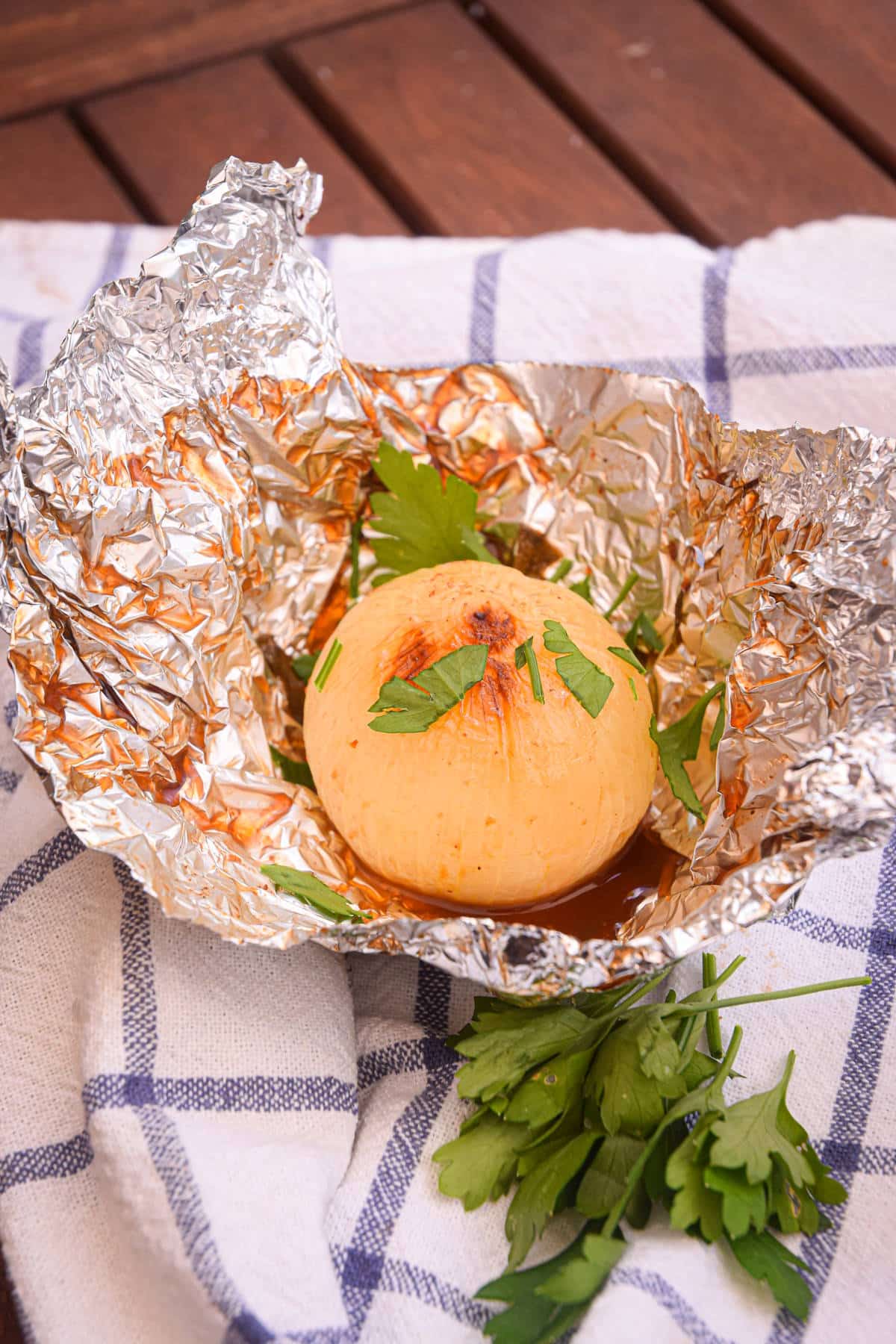 Grilled whole onion on foil with BBQ sauce.