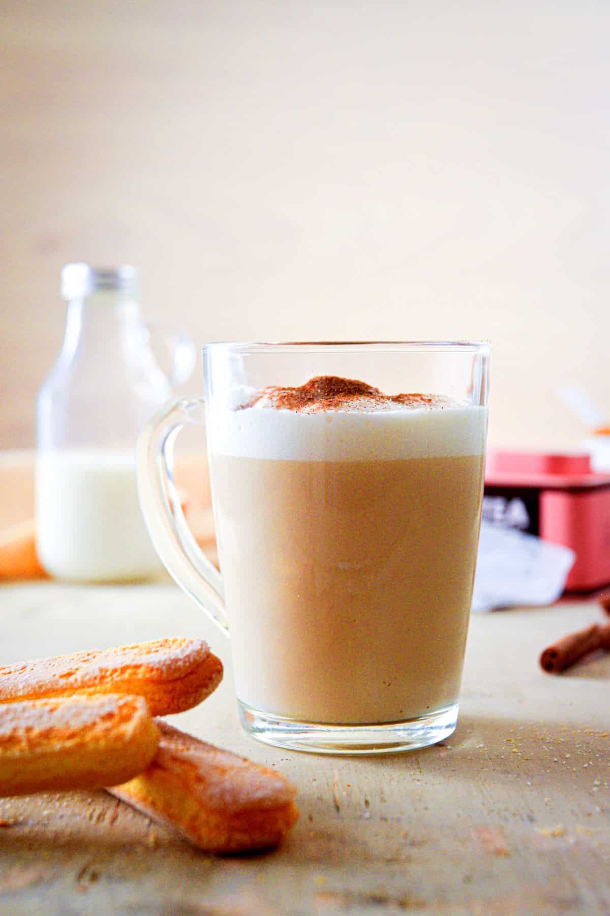 London fog tea latte in a clear glass mug with tea biscuits on the side.