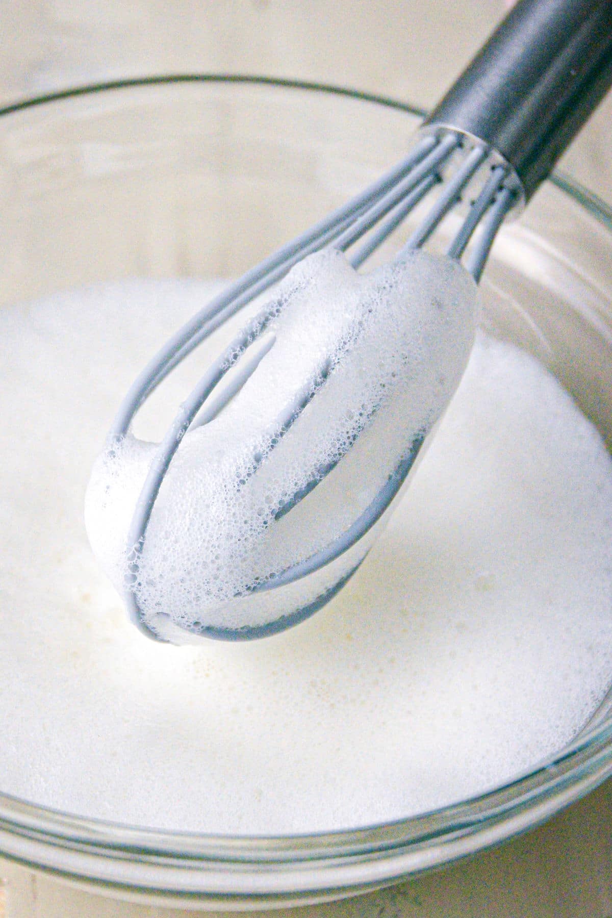 Bowl of frothy milk and a whisk.