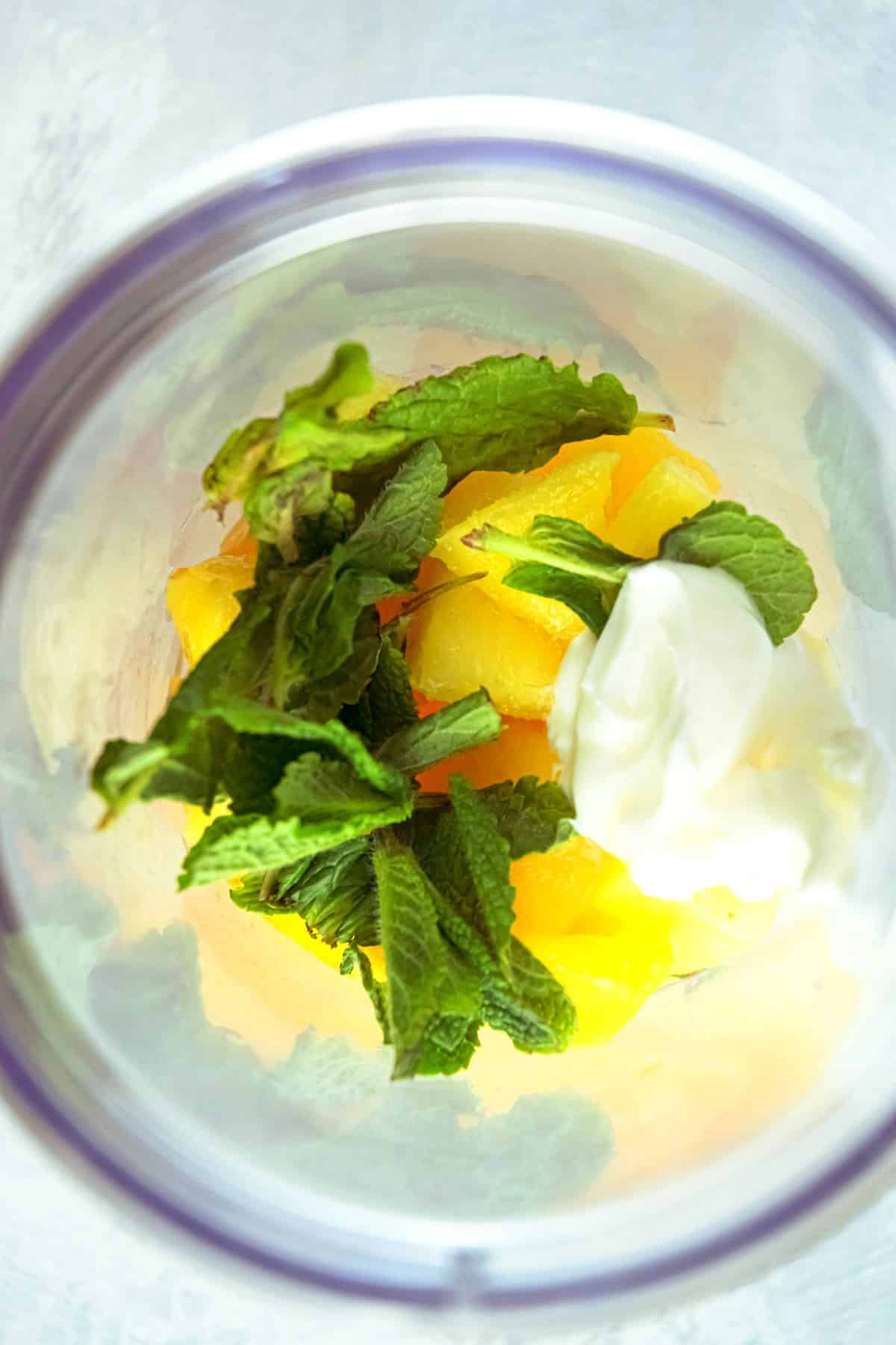 Mango pineapple smoothie ingredients in blender.