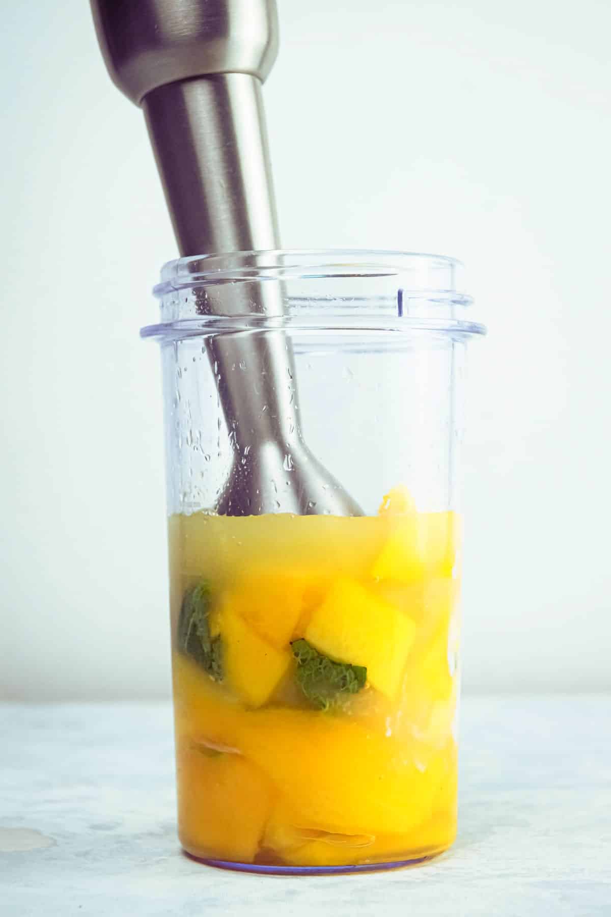 Mango pineapple smoothie ingredients blending in blender jar.