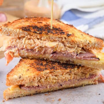 Reuben sandwiches stacked on each other with a toothpick.