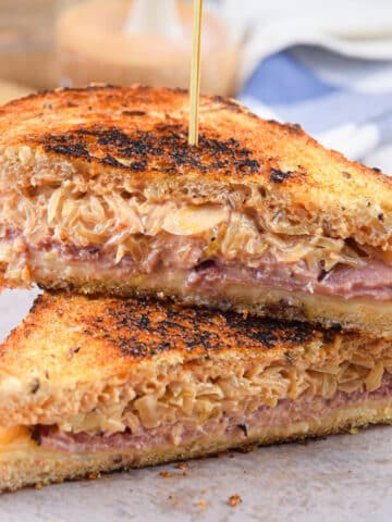 Reuben sandwiches stacked on each other with a toothpick.