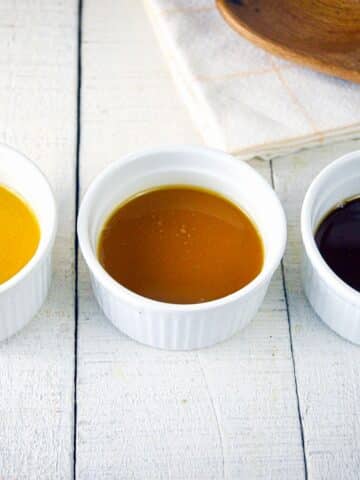 3 colors of roux in ramekins on white wooden background.