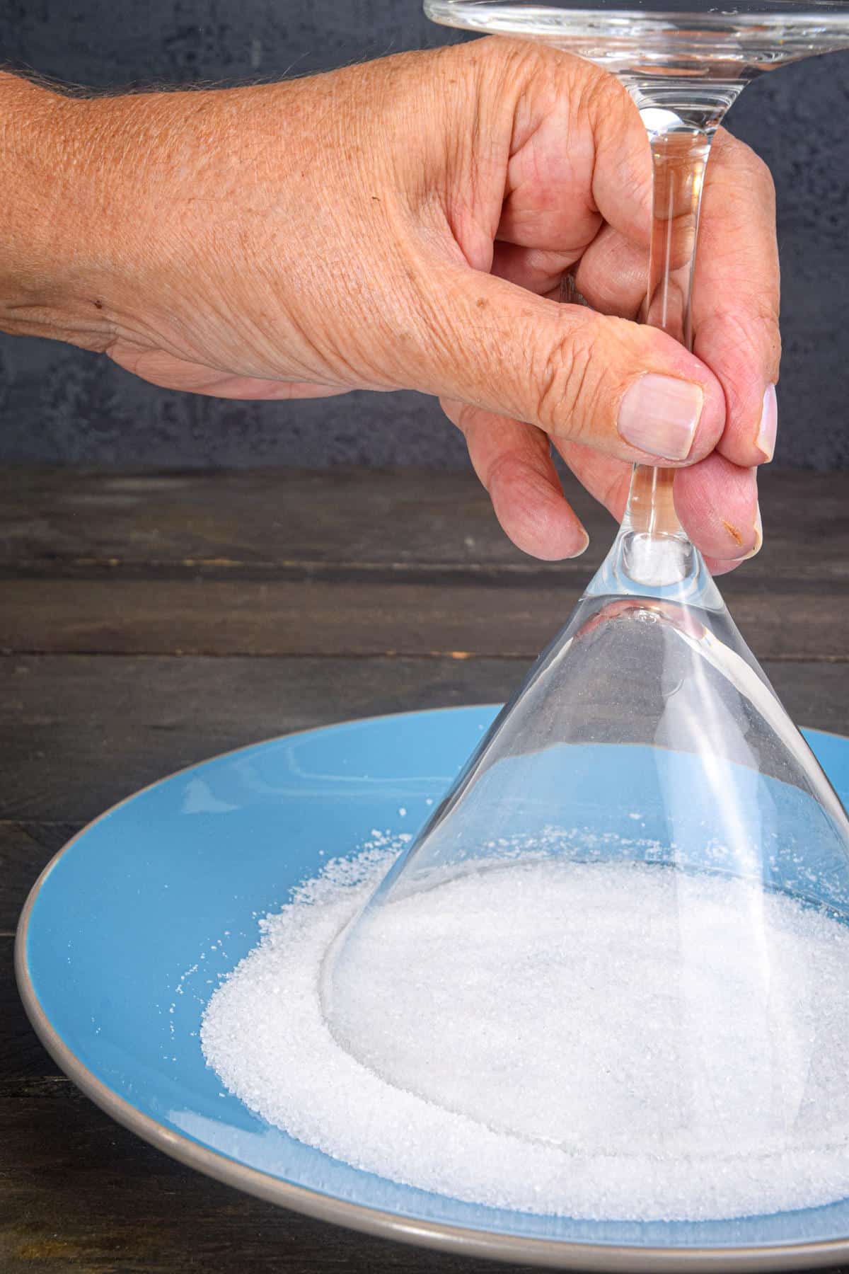 Martini glass dipping into plate of sugar.