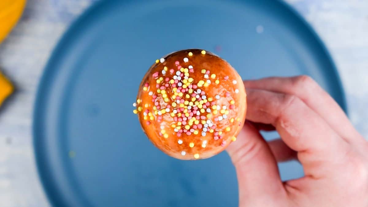 Cake pop with sprinkles in hand.