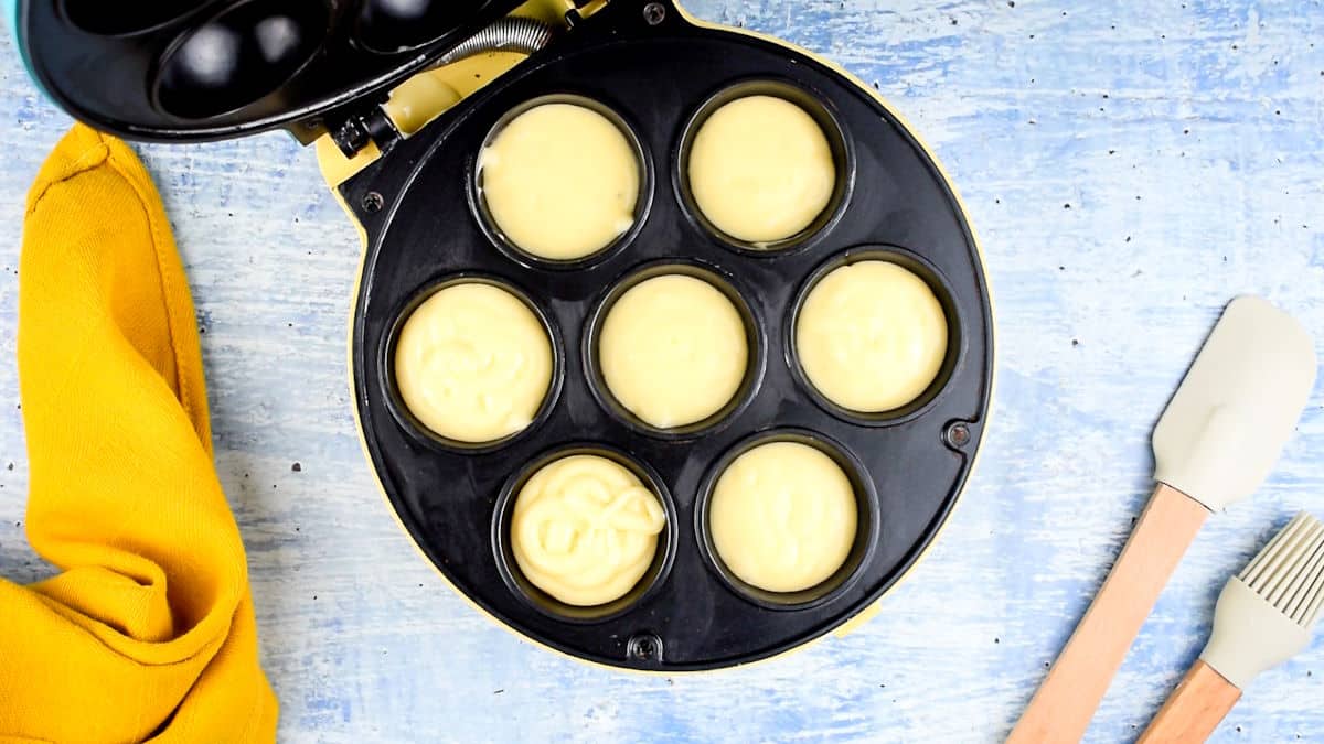 Cake pop maker with cake pop batter in cavities.