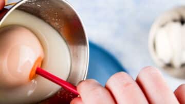 Cake pop in small bucket of coating.