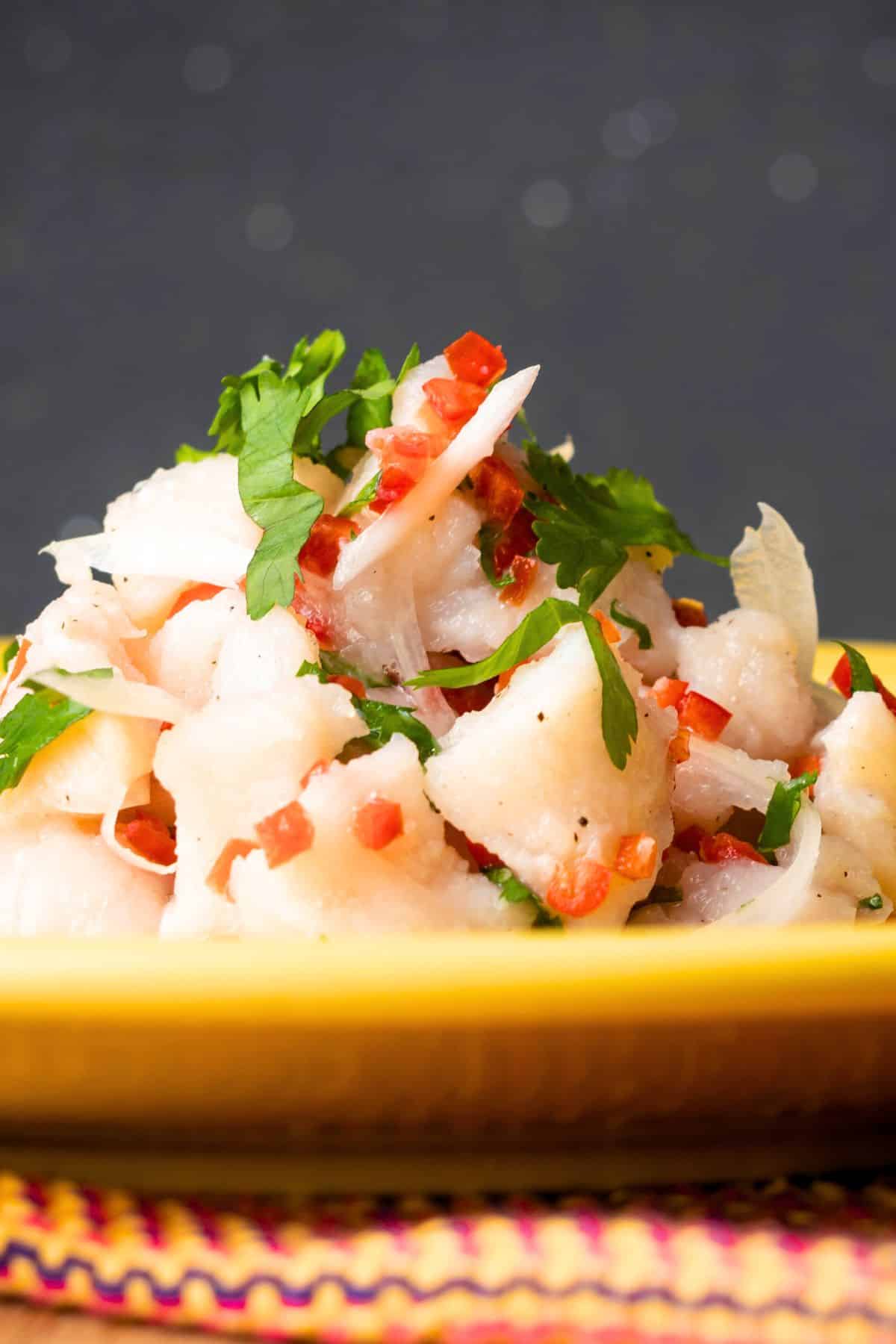 Ceviche on yellow plate garnished with fresh cilantro.