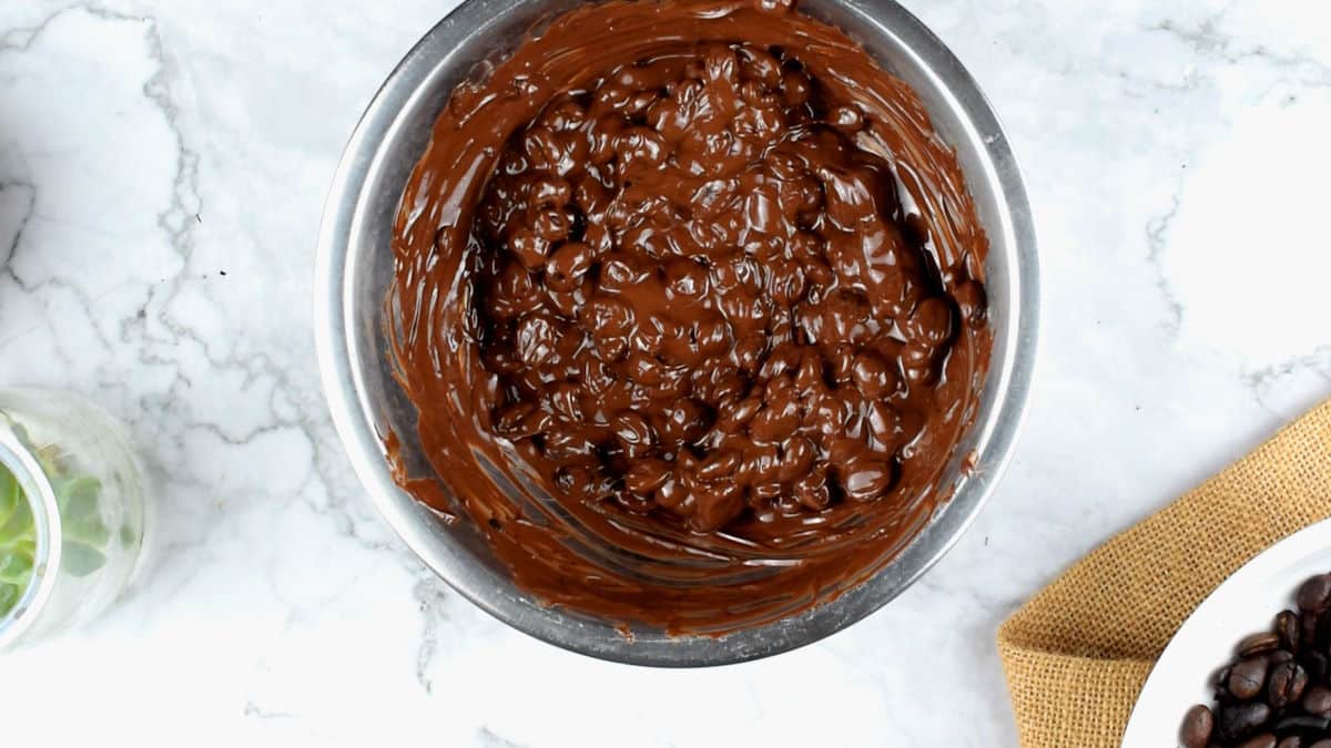 Coffee beans covered in melted chocolate in bowl.