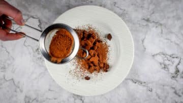 Cocoa powder sprinkling over chocolate covered coffee beans.