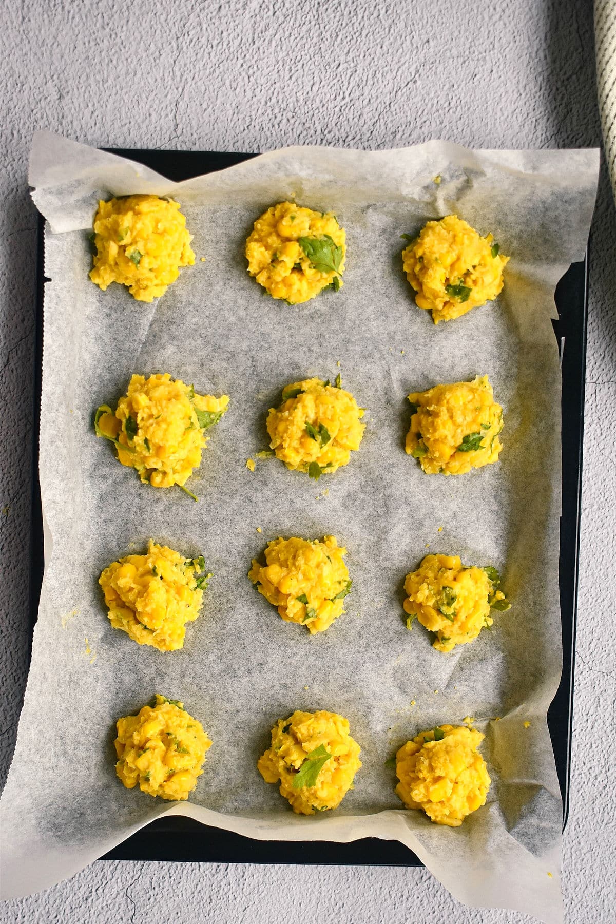 Raw corn nuggets on baking sheet with wax paper.