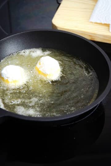 Raw corn nuggets in hot oil in frying pan.