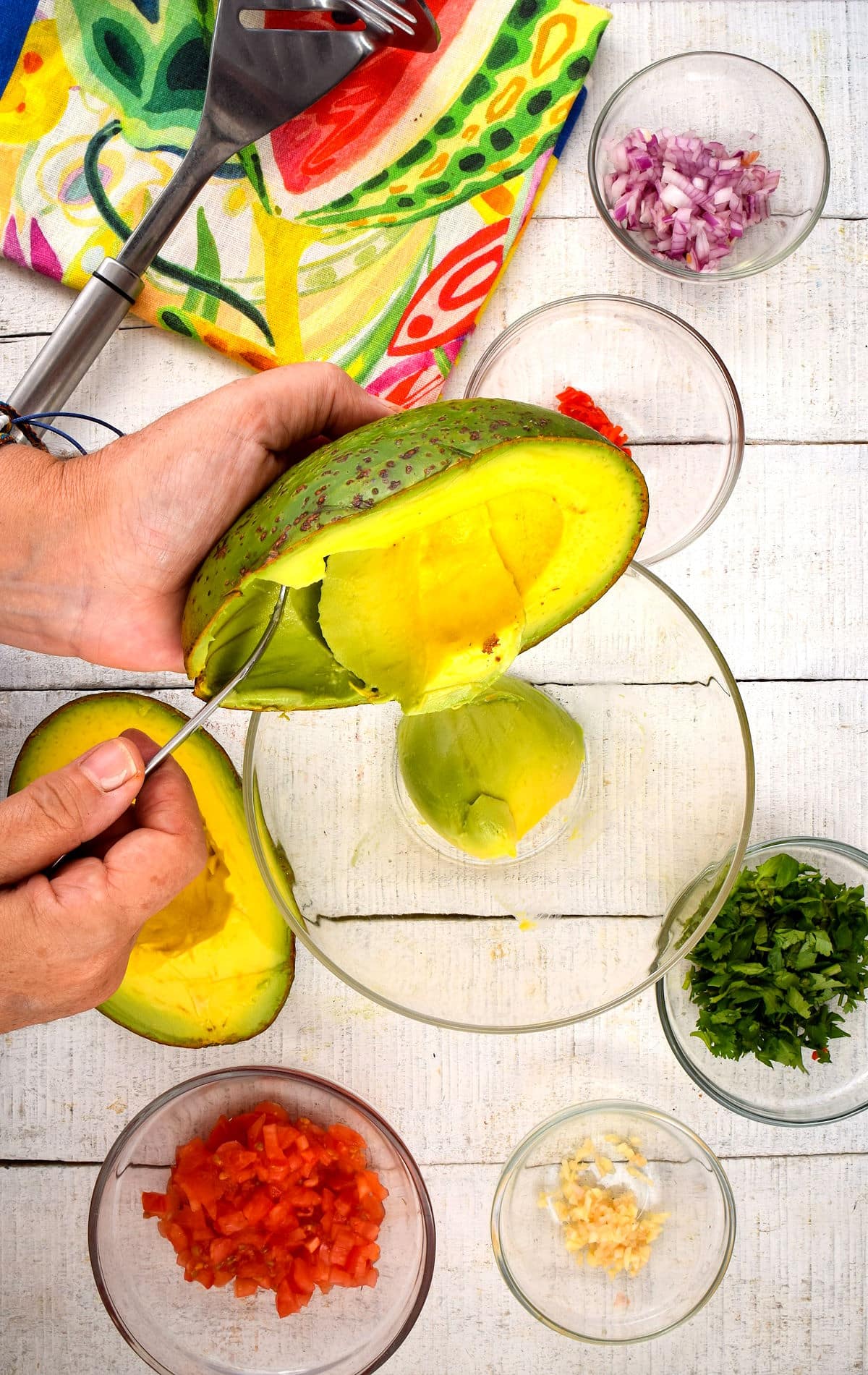 Avocado flesh getting spoon into bowl.