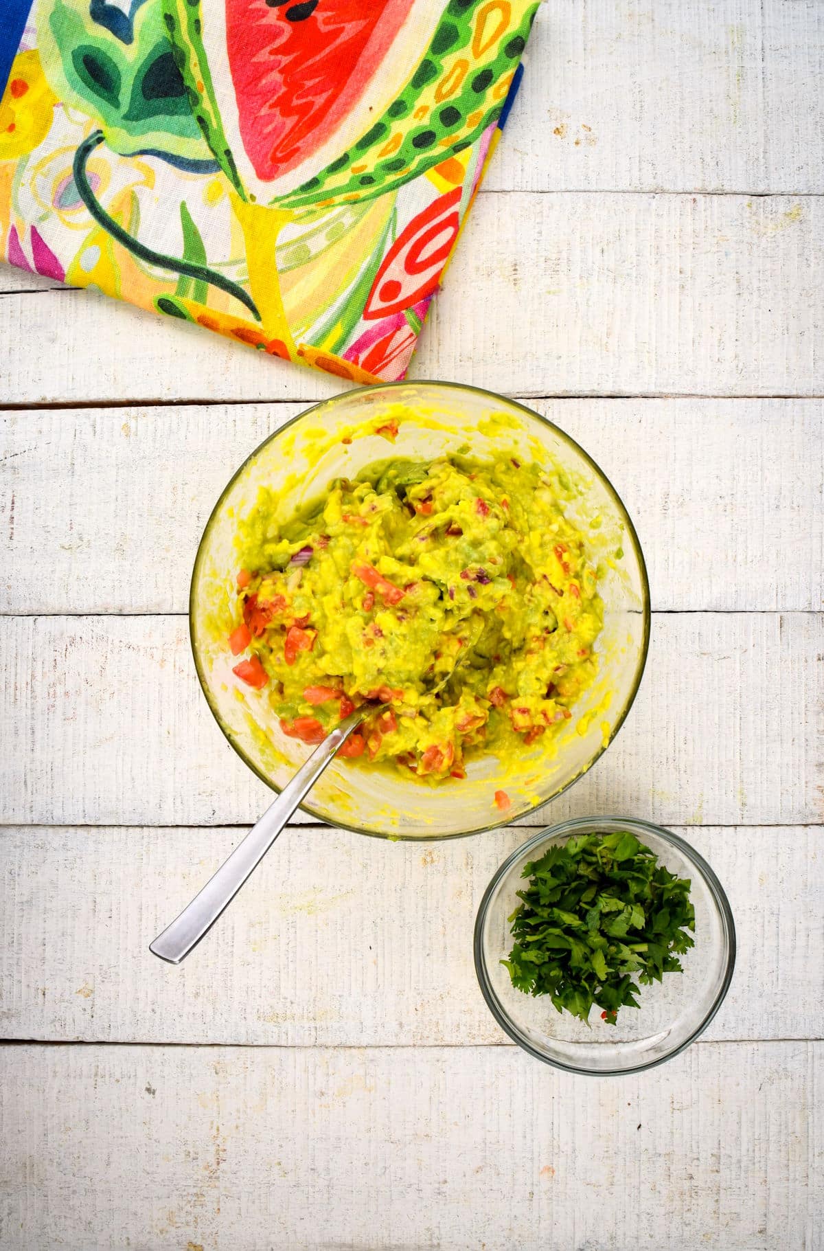 Guacamole and chopped cilantro in bowls.