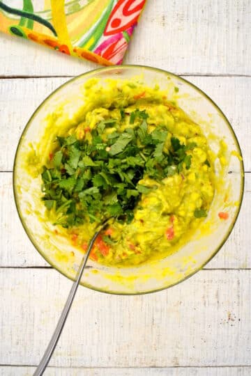 Guacamole in bowl with cilantro and spoon.