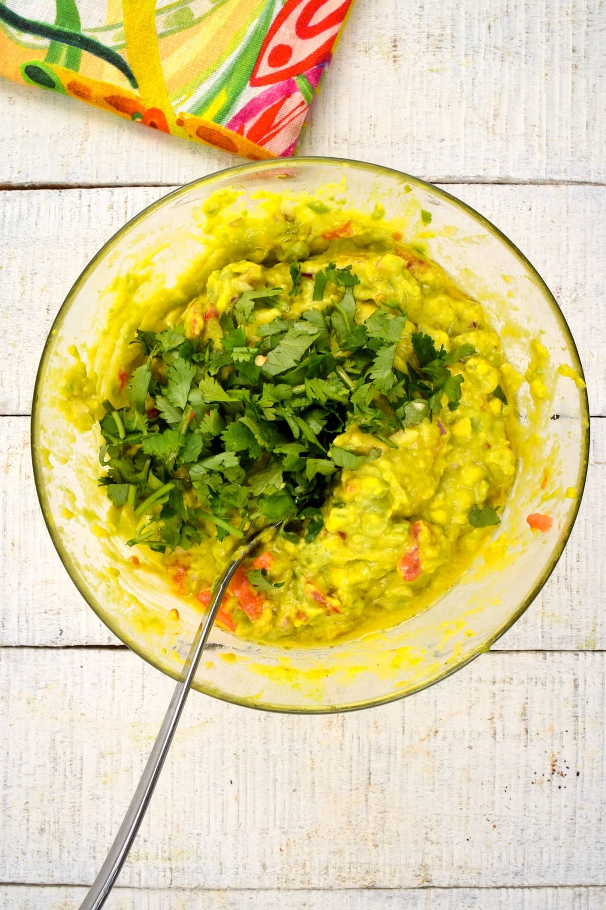 Guacamole in bowl with cilantro and spoon.