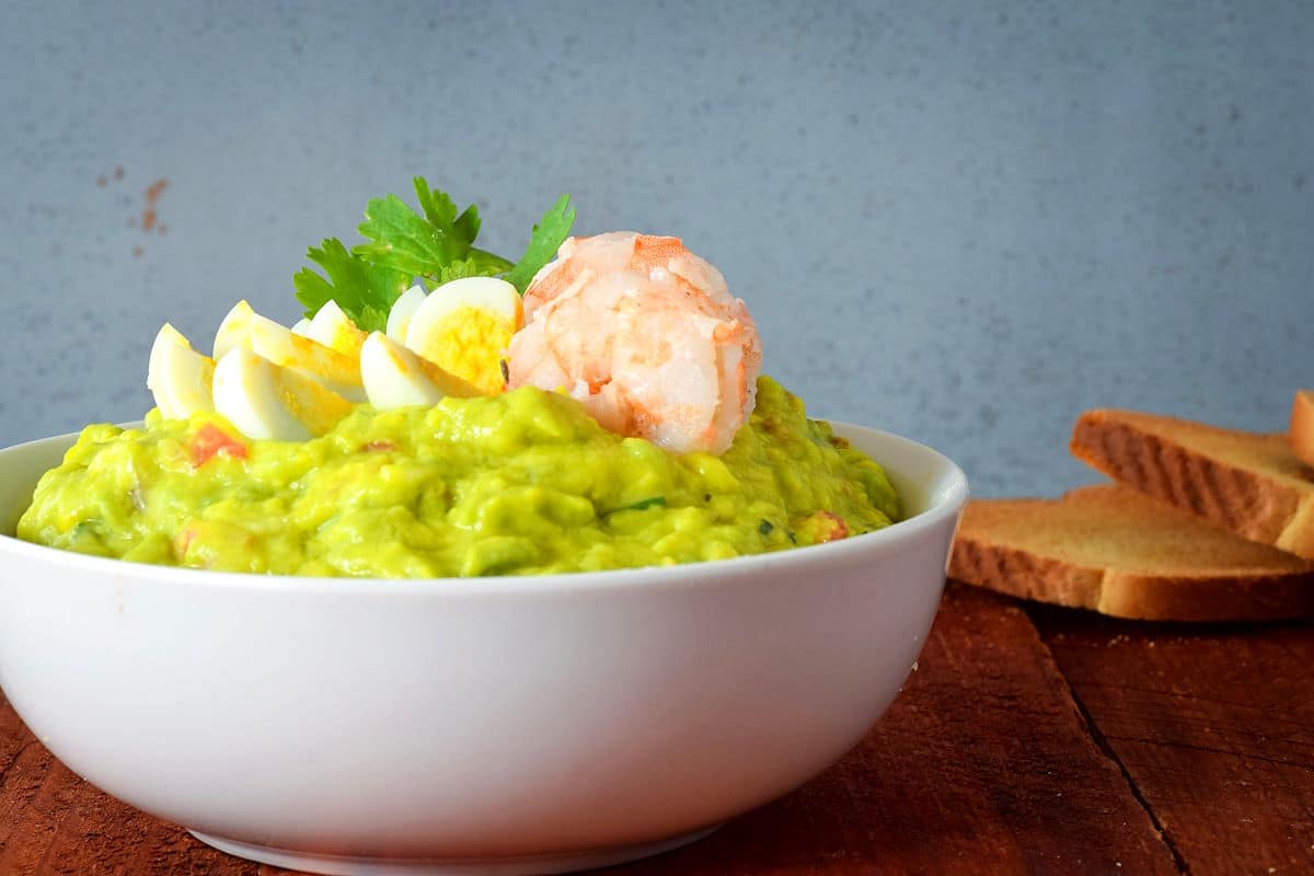 Shrimp and quail eggs in bowl of guacamole.